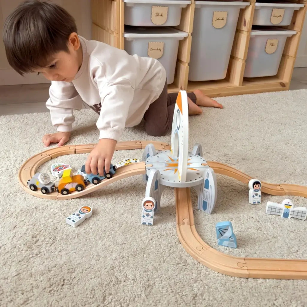 Treno in legno multilivello a tema spaziale con binari, astronauti e razzo. Sviluppa creatività e motricità. Età: 3+ anni.3